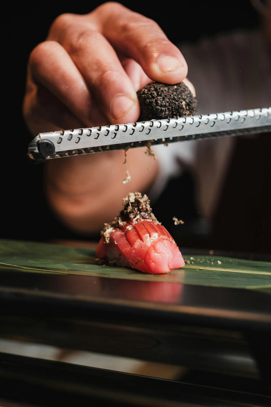 Fresh Black Summer Truffle being shaved on top of a sushi piece